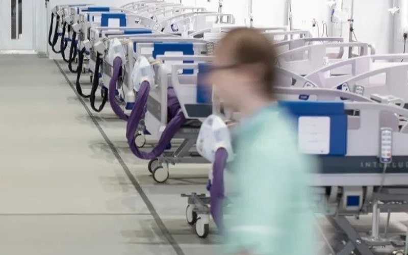 Blue patient record holders mounted on hospital beds in a ward